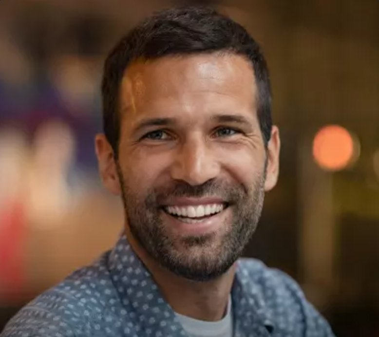 Close-up of a happy, well-groomed man with a vibrant smile, implying healthy teeth or successful dental work.