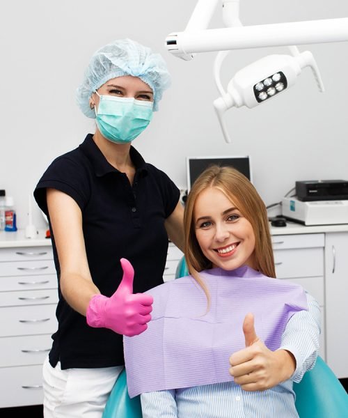 Happy patient and dentist giving thumbs up after a successful dental visit.