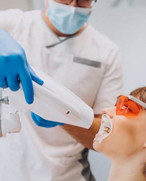 Female patient undergoing professional teeth whitening procedure with protective eyewear