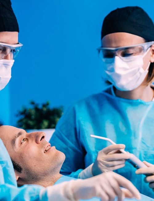 Dental professionals preparing to treat a patient in a sterile environment.