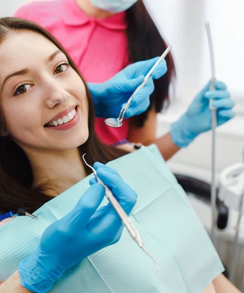 Happy female patient smiling in a dental chair during an examination
