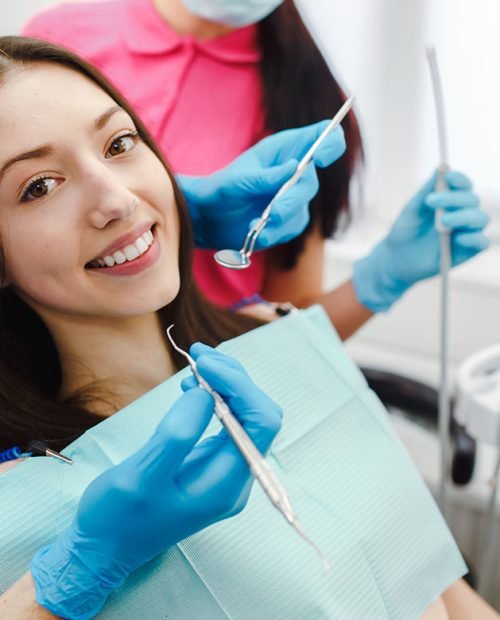 Happy female patient smiling in a dental chair during an examination